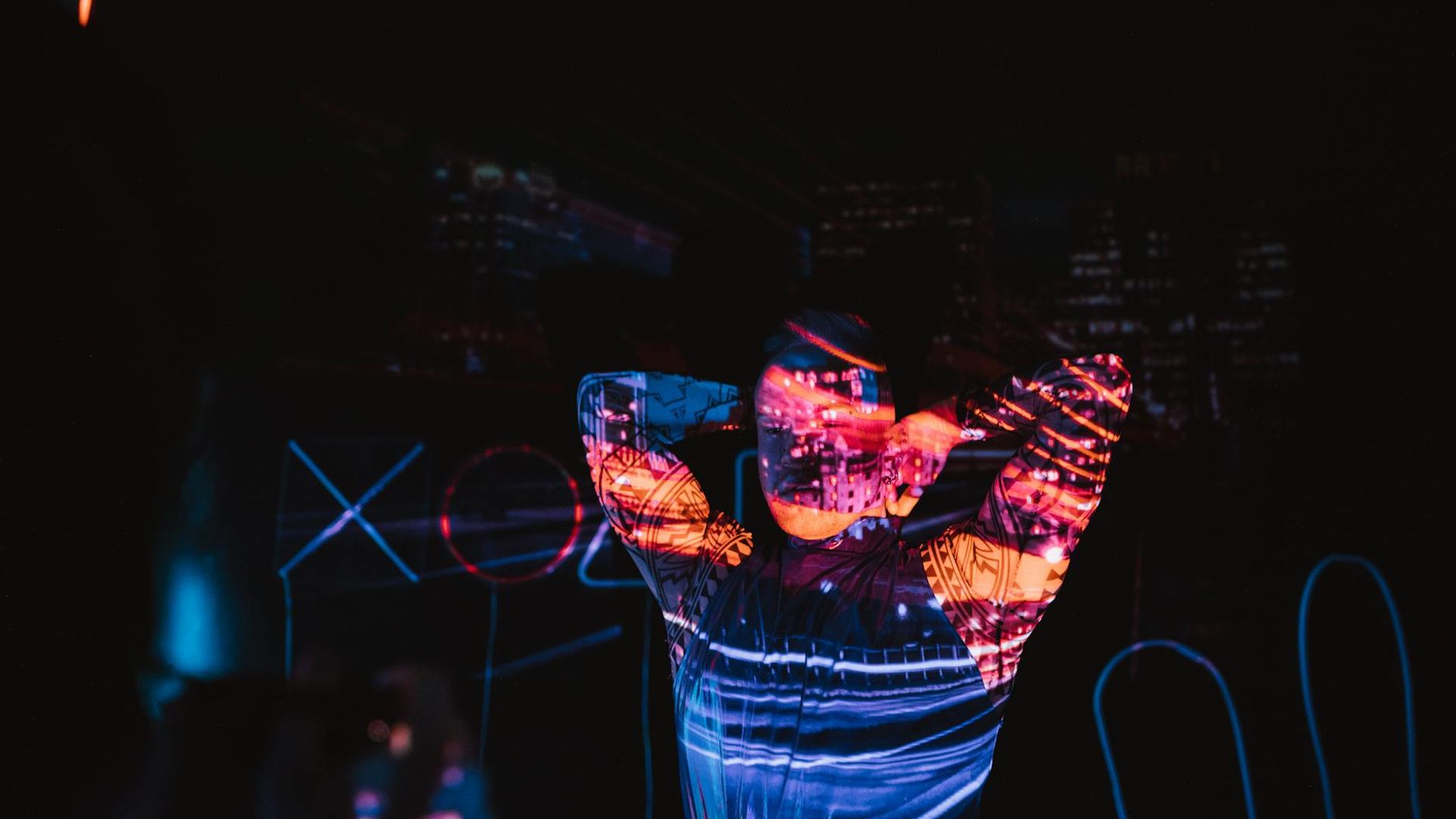 Person practicing yoga in a dark room with neon accents.